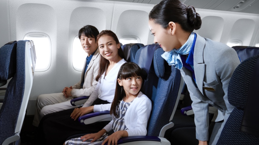 family talking with a cabin attendant in Economy Class