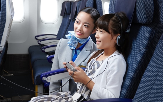 girl and cabin attendant watching in-flight entertainment